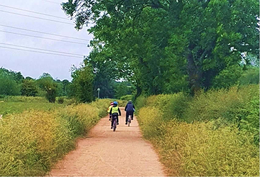 One adult and two children cycling on a rural path
