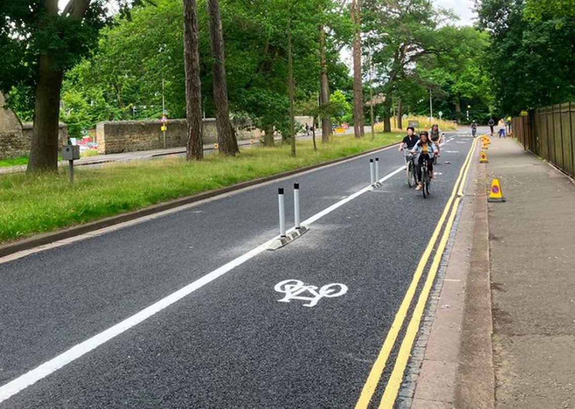 Cyclists riding along lane segregated from cars by posts