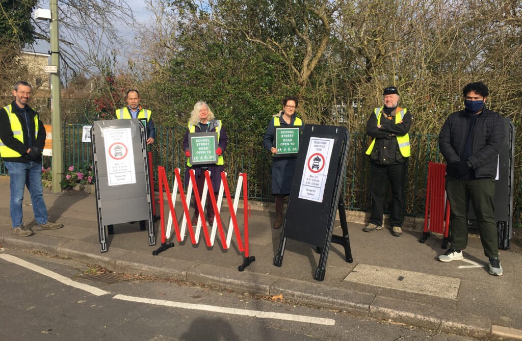 School Streets volunteers stnad with road blocks and signs