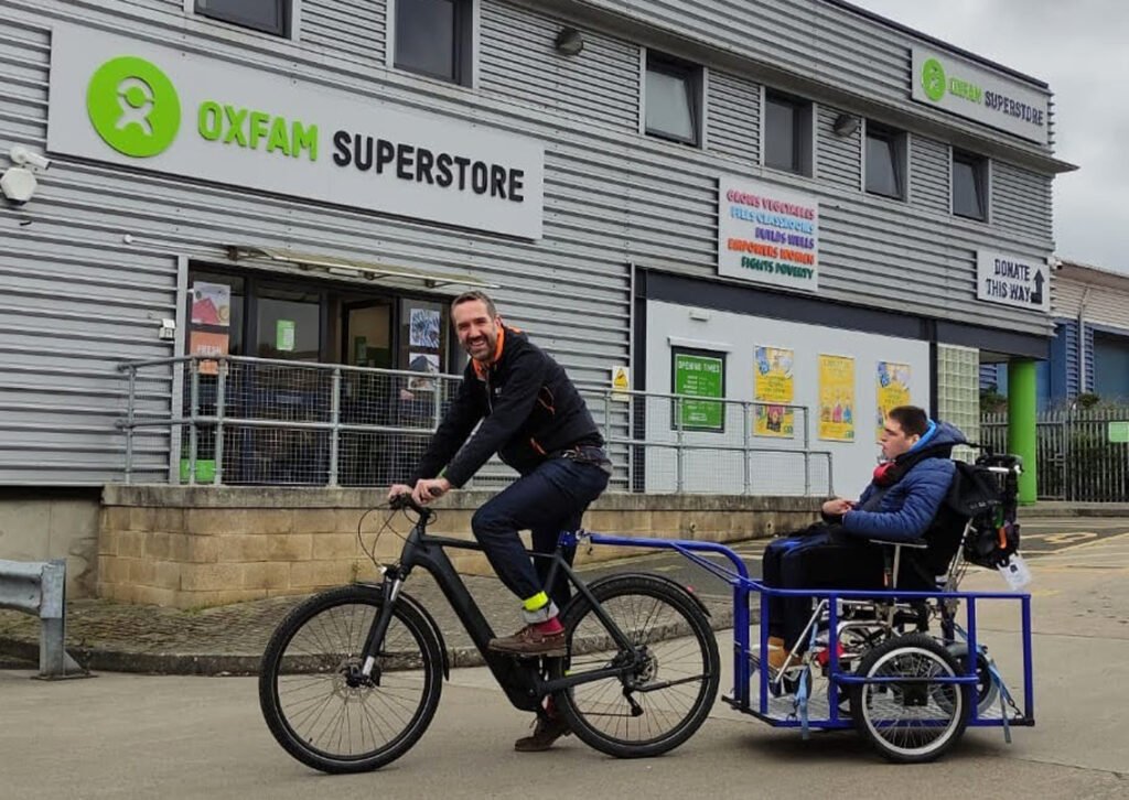 cargo bike towing wheelchair outside Oxfam Superstore