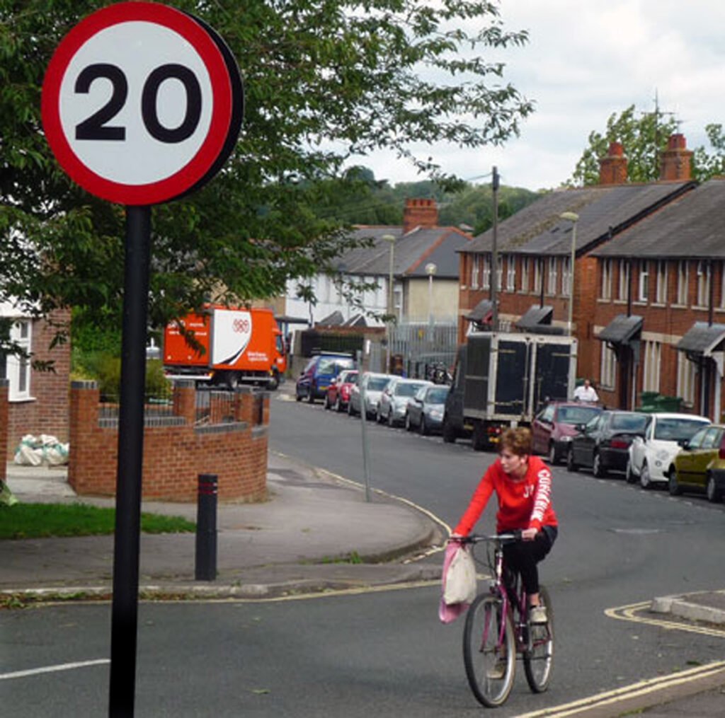 Cyclist in street with 20 mph road sign