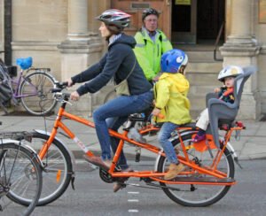 Woman cycling in Oxford with two children in seats on back of bike
