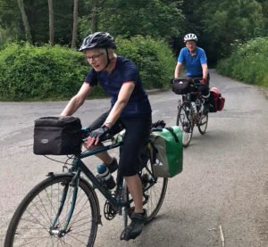 Man and woman cycling uphill with panniers on the back of their bikes