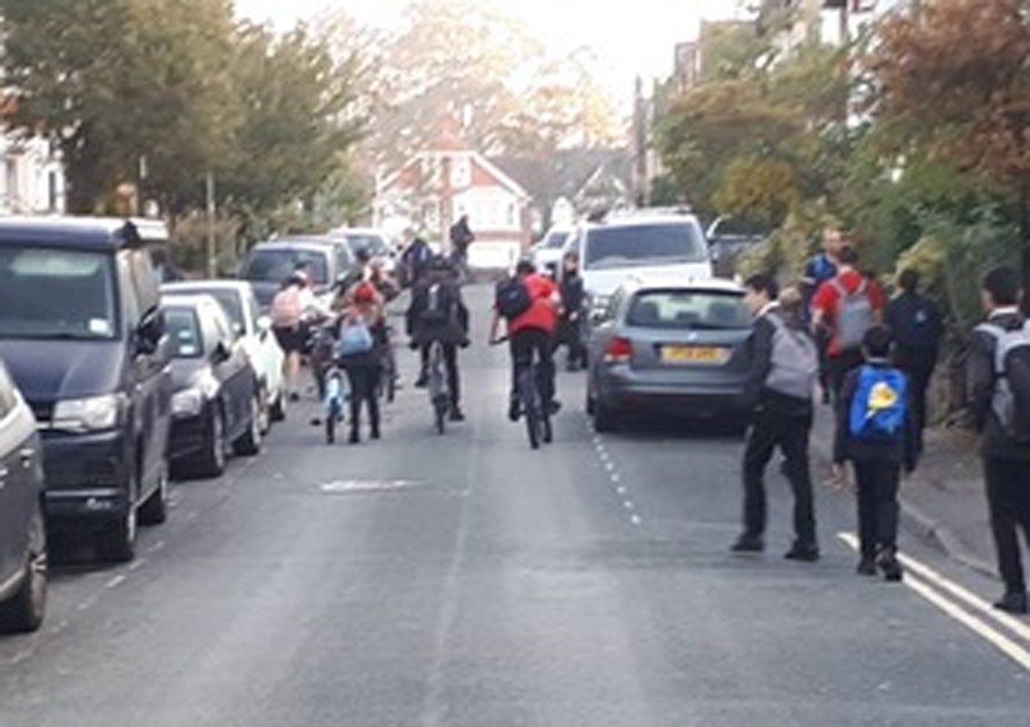 Cyclists and walkers in road with parked cars but no traffic