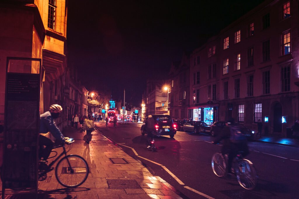 Night view of Oxford High Street with car and bikes using lights