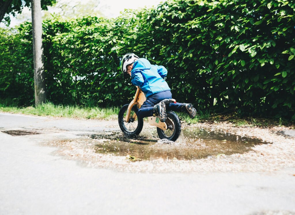 Child on a small balance bike, i.e. a bike with no pedals
