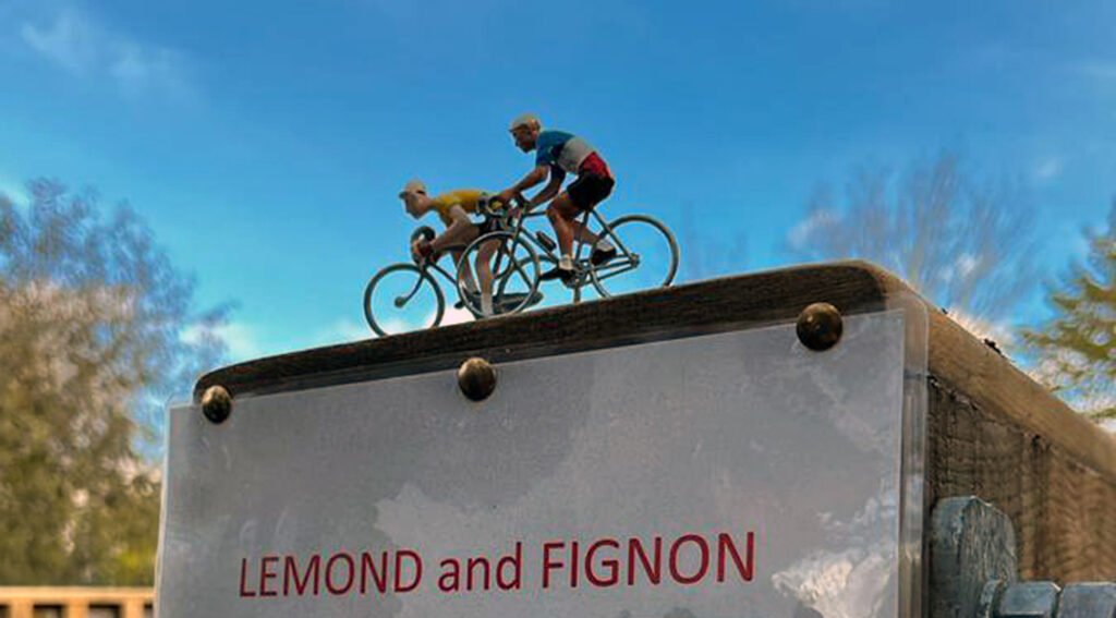Sign saying 'Lemond and Fignon' with tiny model cyclists on top