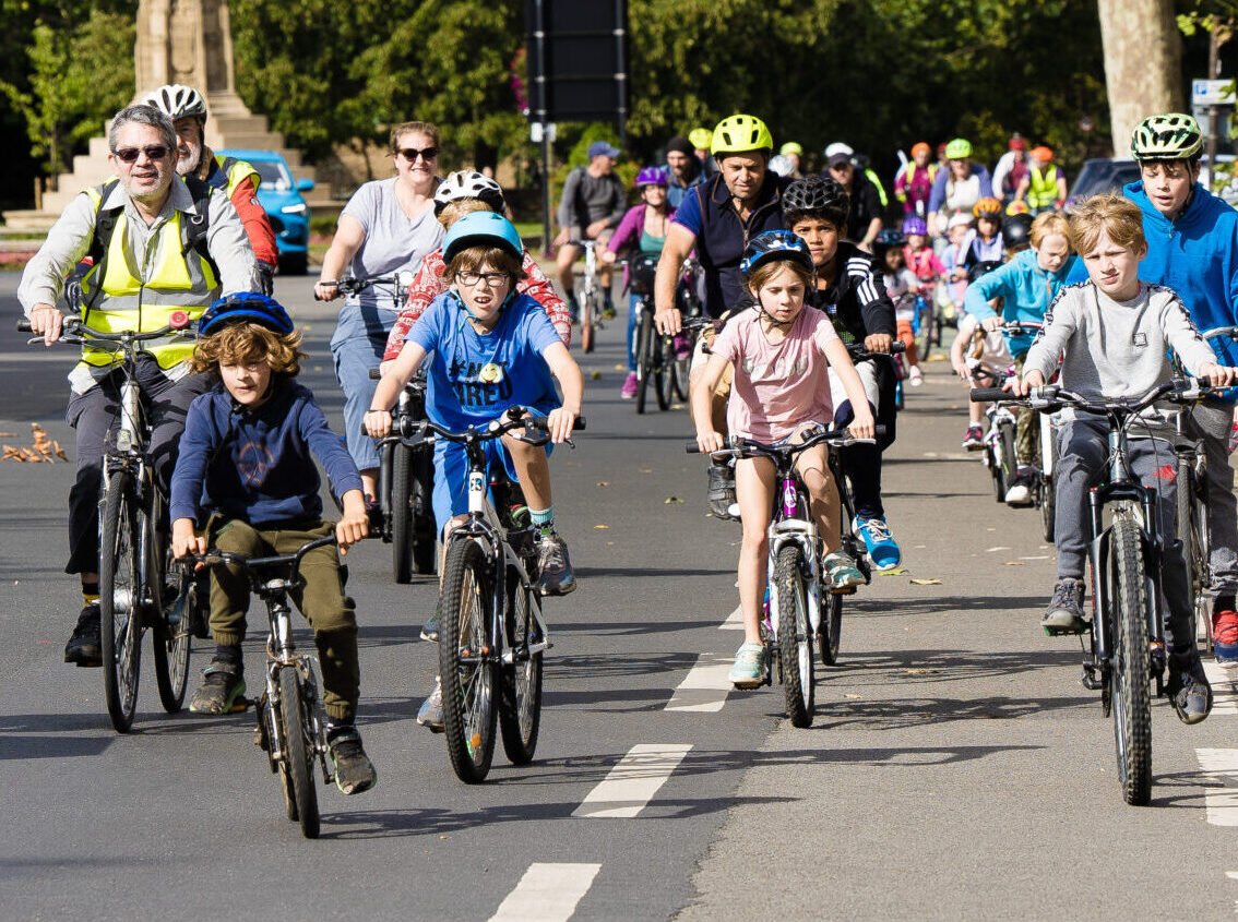 Procession of children cycling from the Plain towards Magdalen Bridge in Oxford. They are flanked by marshals, also on bikes and wearing hi-vis jackets
