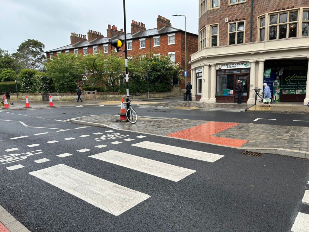 Newly painted zebra crossing with bike crossing painted beside it, shops in background