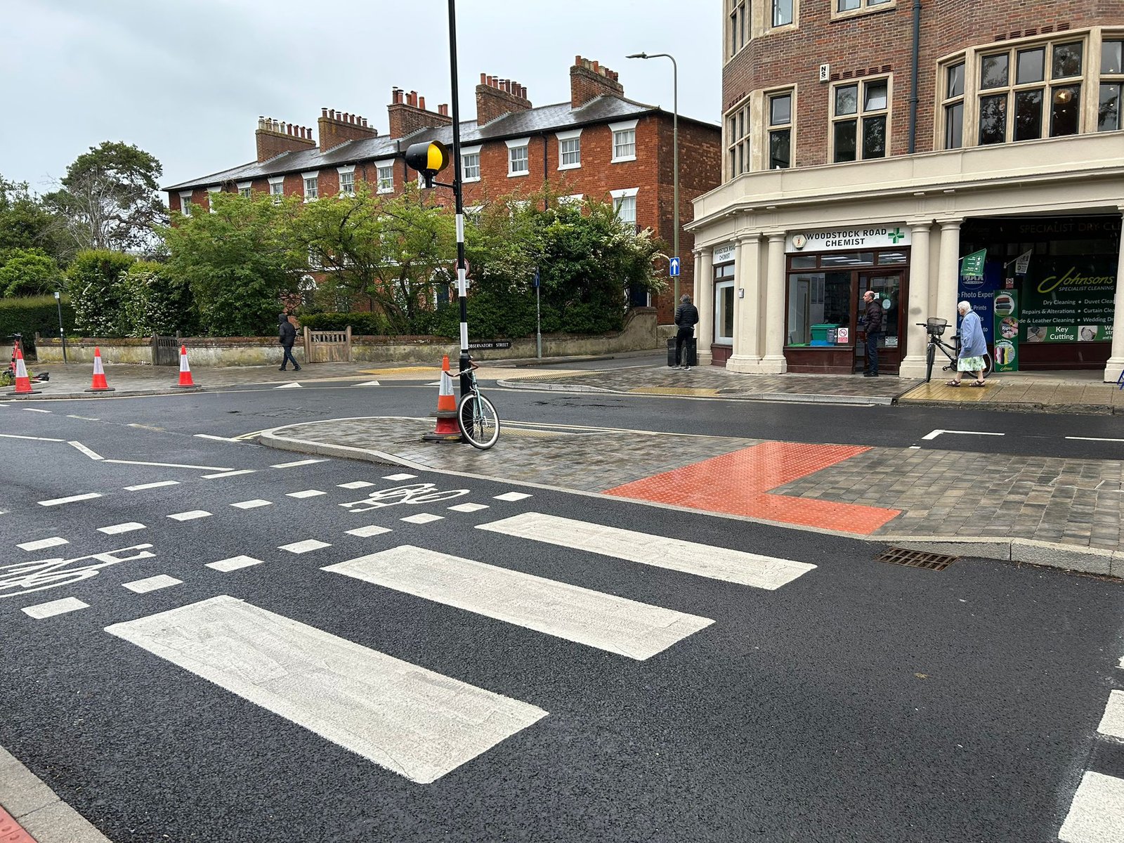 Newly painted zebra crossing with bike crossing painted beside it, shops in background